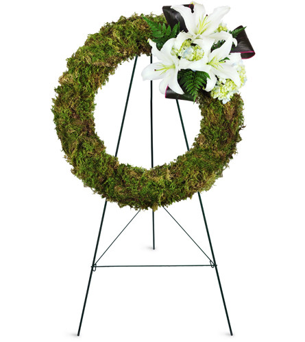 Earth's Jewel Wreath™. An arrangement by Avenue Flowers and Gifts. Green moss, white Oriental lilies, hydrangea, and aspidistra leaves are...