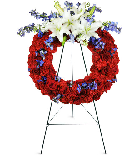 Passionate Grace Wreath™. An arrangement by Avenue Flowers and Gifts. Red roses, red carnations, dark blue Bella Donna, white stock, and white...