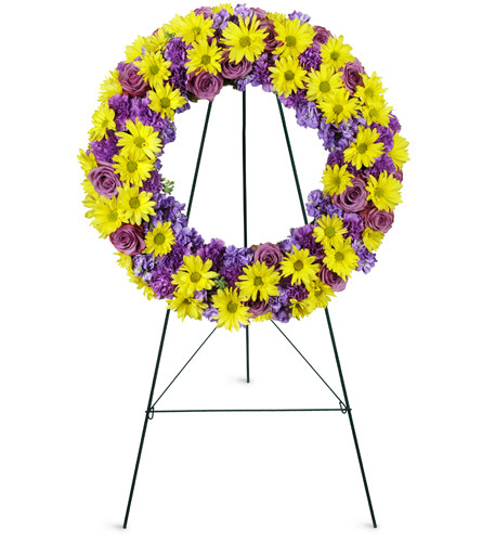 Sunrise Daisy Wreath™. An arrangement by Avenue Flowers and Gifts. Yellow daisies, purple stock, and lavender roses are gracefully arranged for...