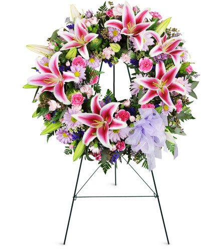 Stargazer Sentiments Wreath™. An arrangement by Avenue Flowers and Gifts. Pink stargazer lilies, mini carnations, and lavender daisies are...